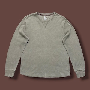 Könnte beinhalten: Ein langärmeliges Shirt mit Rundhalsausschnitt in einem gedämpften Salbeigrün. Das Kleidungsstück besteht aus strukturiertem Waffelstrickstoff, hat einen gerippten Kragen und eine dekorative V-förmige Naht in der Mitte des Ausschnitts.