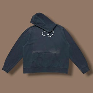 Puede incluir: Una sudadera con capucha azul oscuro con un bolsillo delantero y una capucha con cordón. La sudadera con capucha está hecha de un material suave y tiene mangas largas. La sudadera con capucha es de estilo casual.