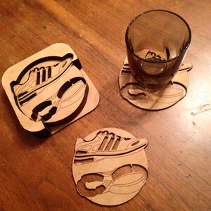 May include: Three wooden coasters featuring a laser-cut design of a running shoe. The coasters are circular and square in shape.