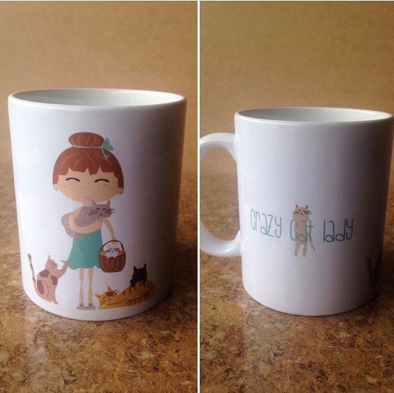 K&ouml;nnte beinhalten: Wei&szlig;e Keramiktasse mit einer Cartoon-Illustration einer Frau mit roten Haaren, die eine Katze h&auml;lt. Die Tasse hat auch eine Cartoon-Katze an der Seite und den Text "Crazy Cat Lady".