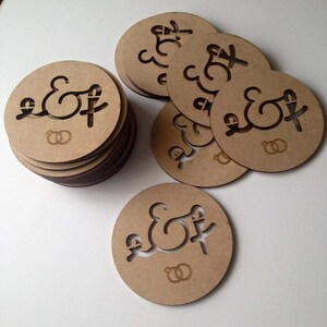 May include: A stack of round, brown wooden coasters with the letters "E & F" and two interlocking rings engraved on them.