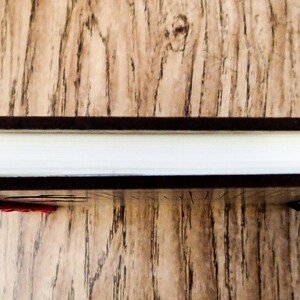 May include: A black spiral bound notebook with a red and white sequin embellishment on the front cover.