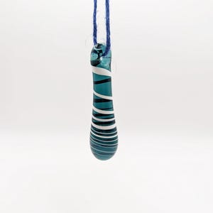 May include: A teal blue glass pendant with white stripes, hanging from a blue cord.