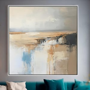 May include: Large abstract landscape painting in a black frame. The artwork features a muted color palette of beige, brown, blue, and white, creating a serene and reflective scene. The painting hangs above a teal sofa with white and teal pillows.