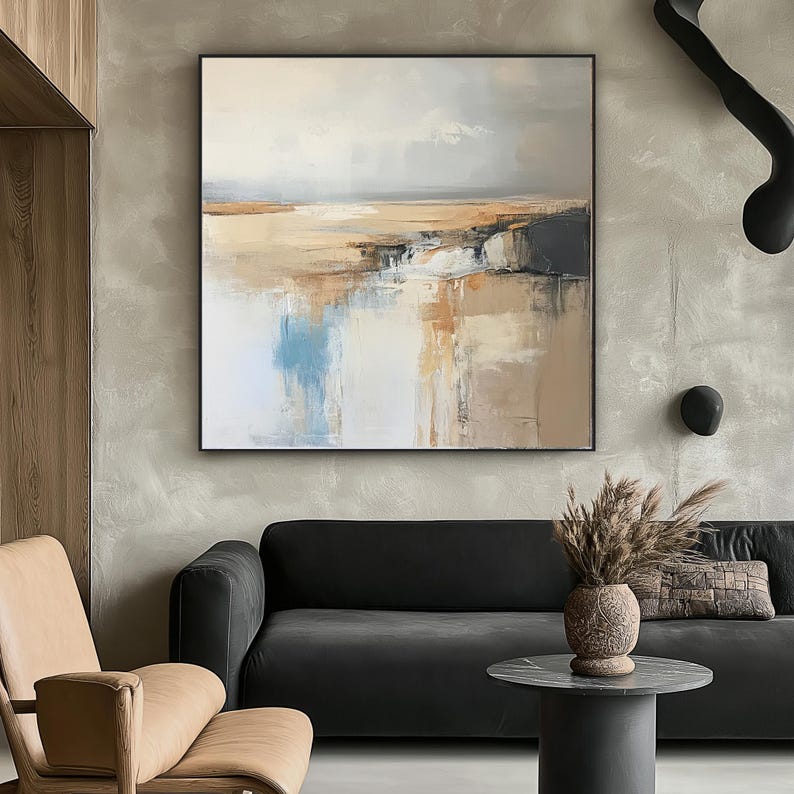 May include: Abstract landscape painting in a black frame. The artwork features a neutral color palette with beige, blue, and white tones. The painting depicts a serene scene with a horizon line and reflective water.