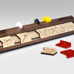 May include: A wooden game board with a set of wooden tiles featuring different symbols. The tiles are arranged in a row on the board. There are also three red arrow-shaped tokens with numbers 1 and 2 on them.