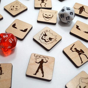 Op de afbeelding: Een bordspel met houten tegels met illustraties van monsters en personages. Er zijn twee dobbelstenen, een rode en een witte, met nummers op elke zijde.