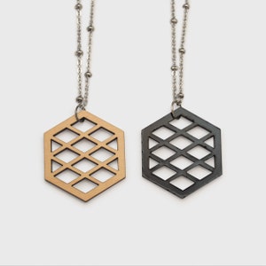 May include: Two necklaces with hexagonal pendants. One pendant is made of natural wood and the other is black. Both pendants have a geometric pattern.