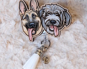 May include: A wooden retractable badge holder with a white tassel. The holder features two dog portraits, one of a German Shepherd and one of a shaggy dog, both with their tongues sticking out.
