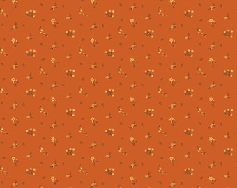 May include: A burnt orange fabric featuring a repeating pattern of small, delicate cream-colored flowers and green leaves. A white ruler at the bottom shows a scale of 12 inches, with the text Riley Blake Designs printed near the start.