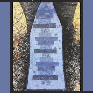 May include: A quilt pattern titled "Frosted Window Panes" with a blue and gray design. The pattern features a central design with horizontal stripes and star accents, set against a background of a tree trunk and a blue border. The designer's name is also included.