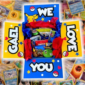 May include: A yellow and blue box with the words "We Love You" and a Pikachu cartoon. The box is filled with snacks and treats.