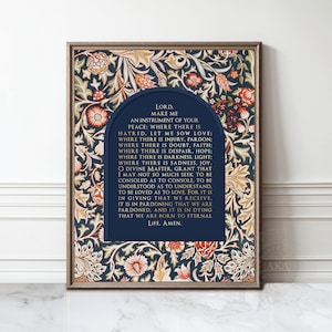 May include: Framed print featuring a navy blue arched text box with the words "Lord, Make Me An Instrument of Your Peace." The background is a floral pattern in navy, cream, and red. The frame is a warm brown.