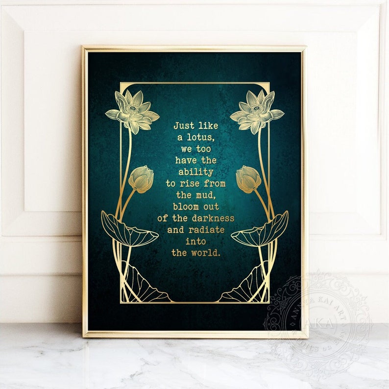 May include: A framed art print with a gold border. The artwork features a teal background with gold lotus flower illustrations and the quote: "Just like a lotus, we too have the ability to rise from the mud, bloom out of the darkness and radiate into the world."