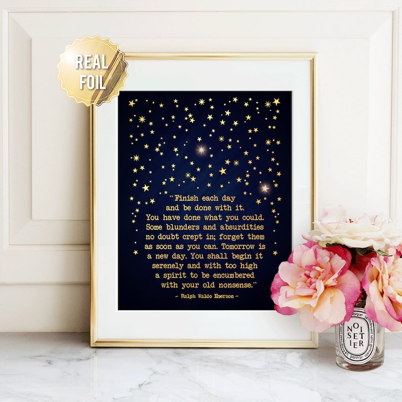 May include: A gold foil print with a dark blue background and gold stars. The print features a quote by Ralph Waldo Emerson: "Finish each day and be done with it. You have done what you could. Some blunders and absurdities no doubt crept in; forget them as soon as you can. Tomorrow is a new day. You shall begin it serenely and with too high a spirit to be encumbered with your old nonsense."