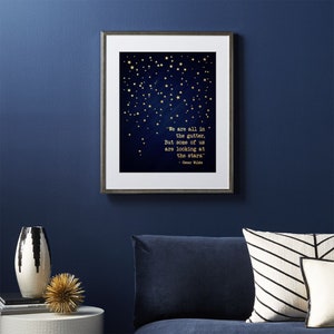 May include: A framed print with a dark blue background and gold stars. The print features a quote by Oscar Wilde: "We are all in the gutter, but some of us are looking at the stars."
