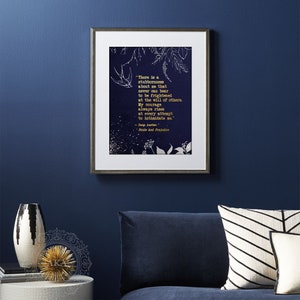 May include: A navy blue framed print with a gold quote from Jane Austen's Pride and Prejudice. The quote reads, "There is a stubbornness about me that never can bear to be frightened at the will of others. My courage always rises at every attempt to intimidate me."