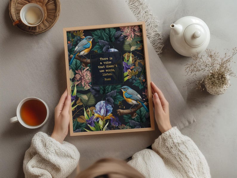 May include: A framed print with a dark background featuring a floral design with two blue birds. The quote "There is a voice that doesn't use words, listen." by Rumi is printed in gold lettering on the print.
