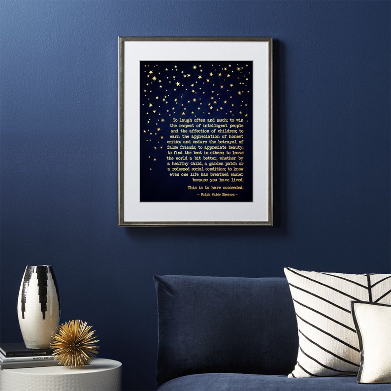 May include: A navy blue framed print with gold stars and a quote by Ralph Waldo Emerson. The quote reads: "To laugh often and much, to win the respect of intelligent people and the affection of children... This is to have succeeded."