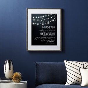 May include: A black and white printable art print featuring a quote by F. Scott Fitzgerald. The quote reads, "We can make the best of the worst of it. I hope you make the best of it. And I hope you see things that startle you. I hope you feel things you never felt before. I hope you meet people with a different point of view. I hope you live a life you're proud of. If you find that you're not, I hope you have the strength to start all over again." The quote is surrounded by a string of white lights.