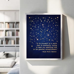 May include: A blue and white framed print with a quote by Ralph Waldo Emerson about being yourself in a world that tries to make you something else. The background is a dark blue with gold stars.