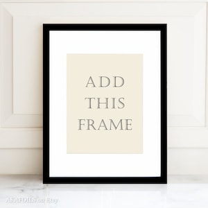 May include: A black picture frame with a white mat and a cream-colored insert. The text "ADD THIS FRAME" is printed in gray on the insert.