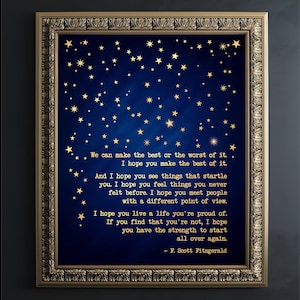 May include: A framed wall art print featuring a deep blue background with gold stars and the quote: We can make the best or the worst of it. I hope you make the best of it. And I hope you see things that startle you. I hope you feel things you never felt before. I hope you meet people with a different point of view. I hope you live a life you're proud of. If you find that you're not, I hope you have the strength to start all over again. - F. Scott Fitzgerald.