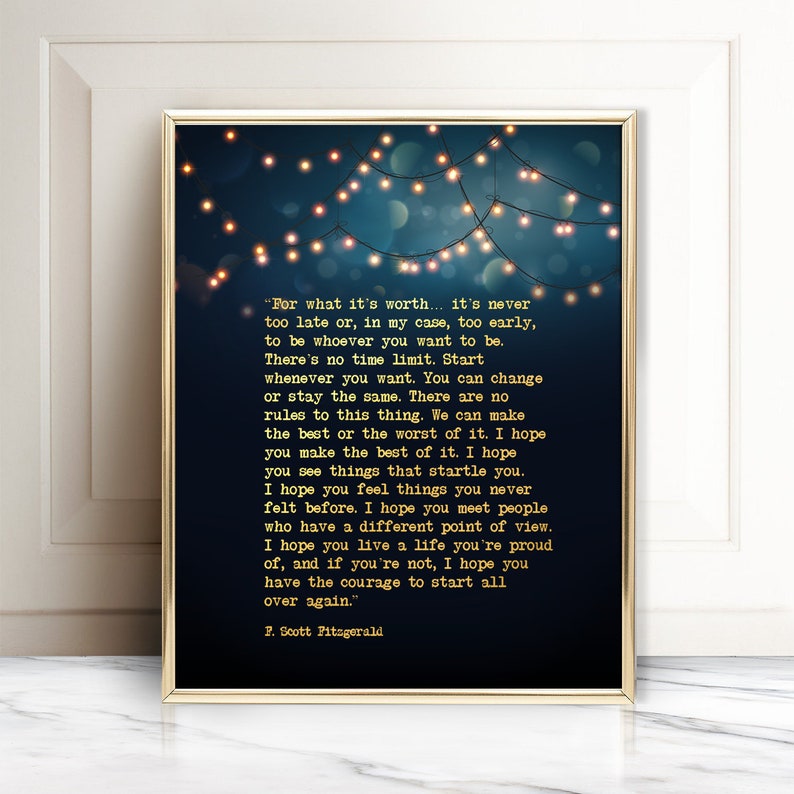 May include: A blue and gold printable wall art print with a quote by F. Scott Fitzgerald. The quote reads, "For what it's worth... it's never too late or, in my case, too early, to be whoever you want to be. There's no time limit. Start whenever you want. You can change or stay the same. There are no rules to this thing. We can make the best or the worst of it. I hope you make the best of it. I hope you see things that startle you. I hope you feel things you never felt before. I hope you meet people who have a different point of view. I hope you live a life you're proud of, and if you're not, I hope you have the courage to start all over again."  The quote is surrounded by a string of gold lights.