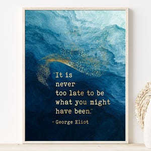 May include: A rectangular wall art print featuring a deep blue and teal watercolor-style background with a gold glitter accent. The text reads: "It is never too late to be what you might have been." - George Eliot, printed in a gold serif font.