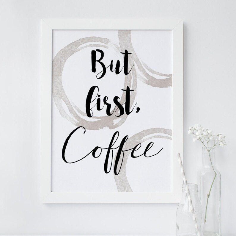 May include: White framed print with the text "But first, coffee" in black cursive font. The background is white with brown coffee ring stains.