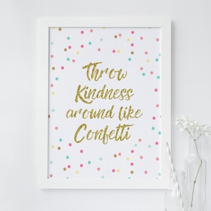 Könnte beinhalten: Ein gerahmter Druck mit der Aufschrift "Throw Kindness around like Confetti" in goldfarbenen Glitzerbuchstaben. Der Hintergrund ist weiß mit bunten Konfettipunkten. Der Rahmen ist weiß, und eine Glasflasche mit Strohhalm und Blumen ist im Hintergrund.