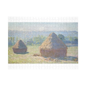 Puede incluir: Un rompecabezas que presenta una pintura de paisaje de dos montones de heno en un campo. Los montones de heno son de color marrón dorado, sobre un fondo de campos verdes y un cielo azul brumoso. El rompecabezas es de forma rectangular.