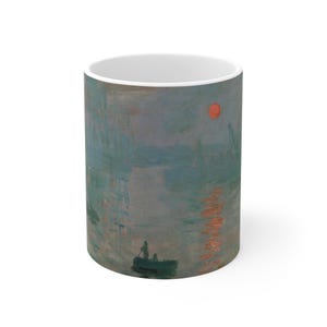 May include: White ceramic mug featuring a print of a famous Impressionist painting. The artwork depicts a sunrise over a body of water with a small boat and figures. The color palette includes shades of blue, orange, and gray.