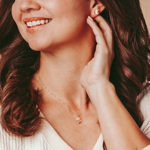 Herkimer Diamond Stud Earrings worn by a smiling woman with a matching Herkimer Diamond necklace. Quartz crystals wrapped three times in gold wire for completed post earrings. The quartz crystals are transparent, colorless, and naturally faceted.