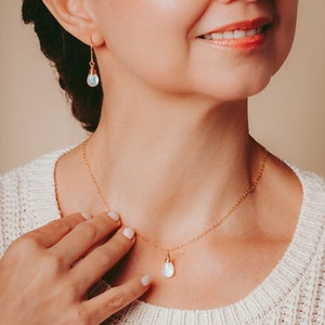 Puede incluir: Un collar de cadena dorada con un colgante de piedra lunar en forma de l&aacute;grima. El collar se combina con pendientes de piedra lunar a juego.