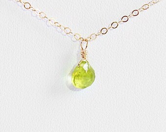 May include: A delicate gold chain necklace with a single, light green gemstone pendant.