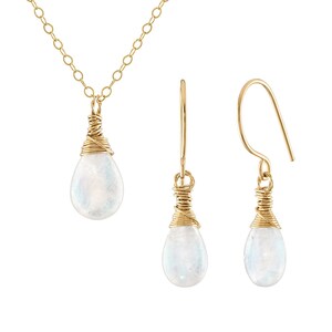 Puede incluir: Un conjunto de collar y pendientes de oro con un colgante de piedra lunar en forma de l&aacute;grima y pendientes a juego. La piedra lunar est&aacute; envuelta en alambre de oro.