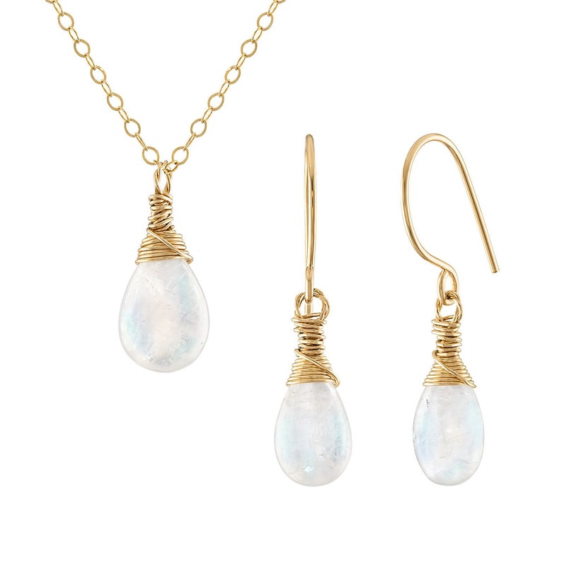 Puede incluir: Un conjunto de collar y pendientes de oro con un colgante de piedra lunar en forma de l&aacute;grima y pendientes a juego. La piedra lunar est&aacute; envuelta en alambre de oro.