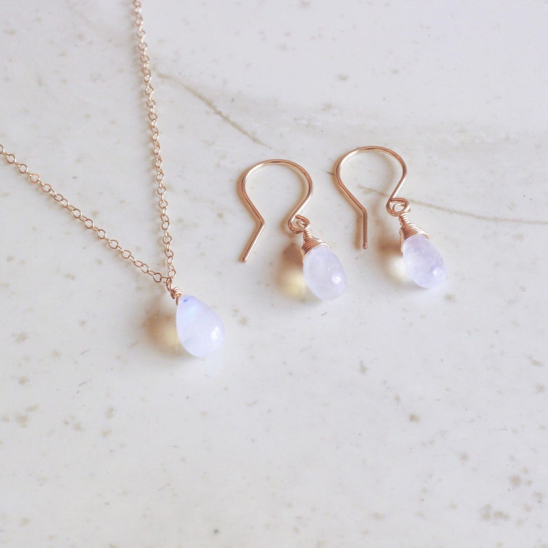 Puede incluir: Un conjunto de delicados pendientes de oro y un collar con colgantes de piedra lunar en forma de l&aacute;grima.