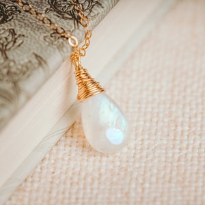 Puede incluir: Un collar de cadena de oro con un colgante de piedra de luna en forma de l&aacute;grima envuelto en alambre de oro.