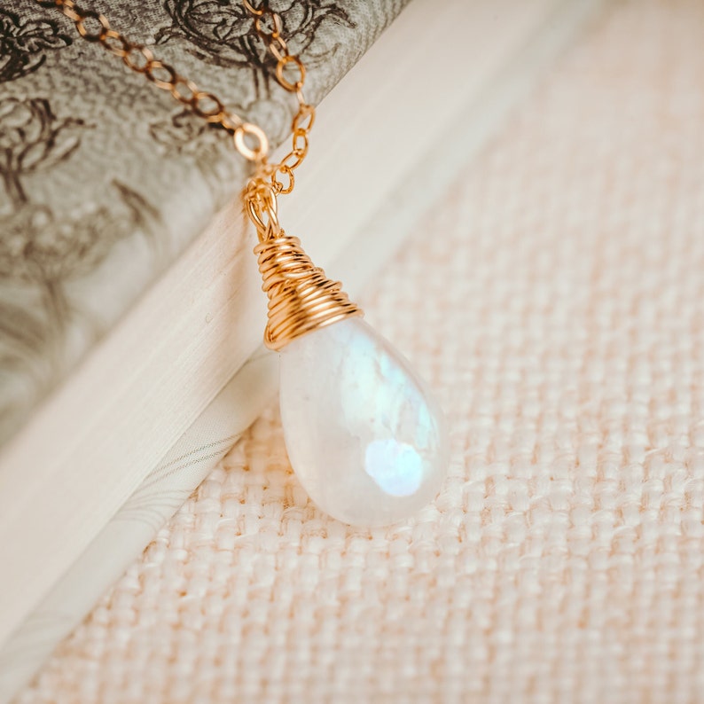 Puede incluir: Un collar de cadena de oro con un colgante de piedra de luna en forma de l&aacute;grima envuelto en alambre de oro.