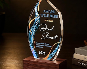 May include: A flame-shaped clear glass award plaque mounted on a rectangular dark wood base. The glass features blue and gold swirling abstract patterns and text that reads: AWARD TITLE HERE, PRESENTED TO, Derek Stewart, IN RECOGNITION FOR YOUR DEDICATION AND OUTSTANDING PERFORMANCE, 2026.
