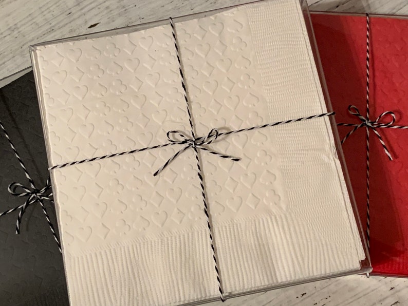Puede incluir: Tres cajas de regalo envueltas en papel blanco, negro y rojo con lazos de cuerda negra y blanca. La caja blanca tiene un patr&oacute;n de corazones.