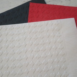 Puede incluir: Tres hojas de cartulina texturizada en negro, rojo y blanco. Cada hoja tiene un patr&oacute;n repetido de s&iacute;mbolos de cartas de juego.