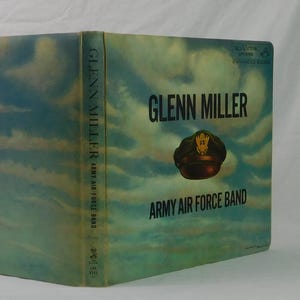 May include: Vintage vinyl record album cover for Glenn Miller and the Army Air Force Band. The cover features a sky-themed background with the band's name and a military cap illustration.