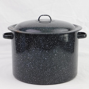 May include: A large, black speckled enamelware pot with a matching lid. The pot has two side handles and a loop handle on the lid. The pot is designed for cooking and food preparation.