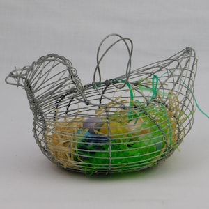 May include: A wire basket shaped like a chicken, filled with colorful Easter eggs and decorative straw. The basket has a handle and a bird-like head. The eggs are various colors, including purple, yellow, and blue. The basket is a festive decoration.