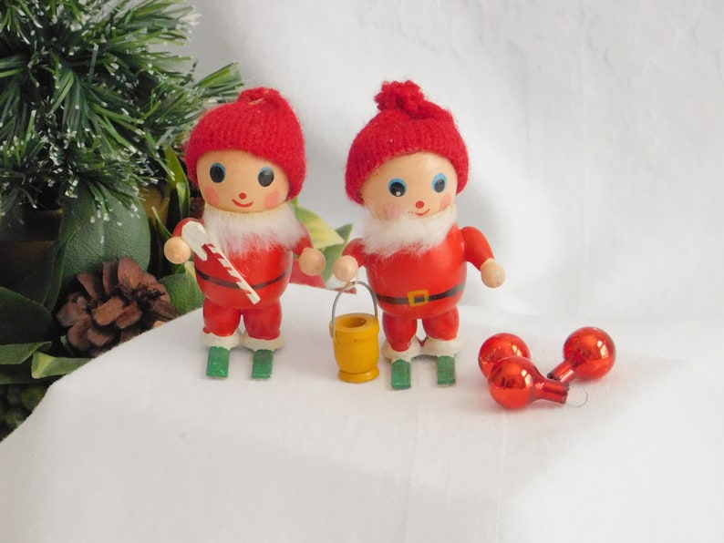 Set of 2 wooden handpainted Santa Clauses on wooden skis wearing red knitted toboggans Christmas trees ornaments /& other kitschy displays.