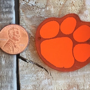 Peut inclure: Deux ornements en acrylique en forme de patte d'ours orange. Les empreintes de pattes sont à peu près de la taille d'une pièce de monnaie française.