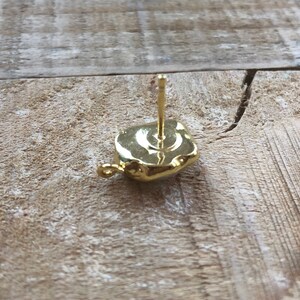 May include: Gold earring with a square-shaped stone. The earring has a post and a small loop on the back.